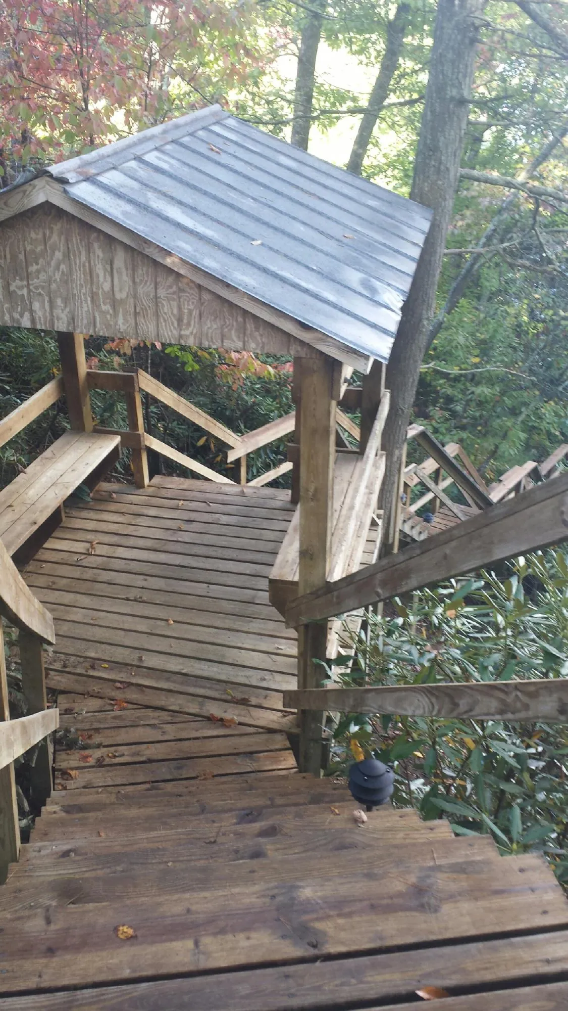 Metal roofed shelter over wooden steps on a wooded walkway — Skylight Repair & Installation work by our crew in Yazoo City