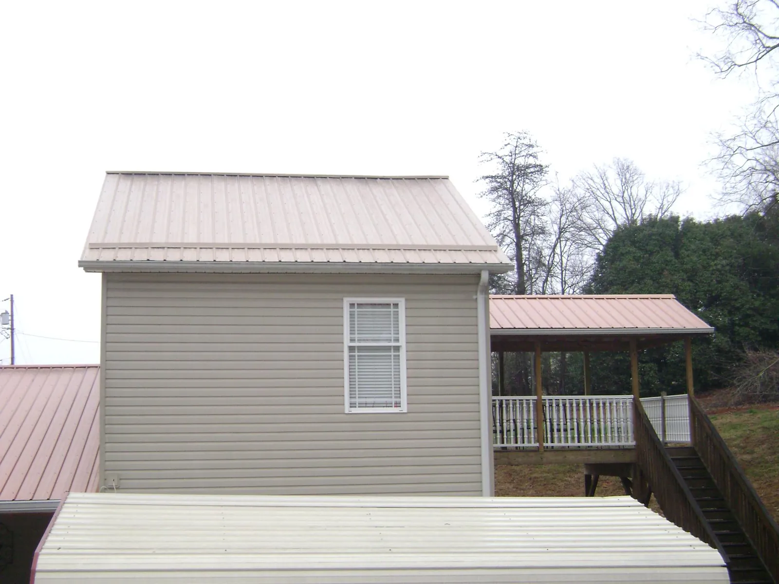 Tan metal roofs on a two story addition and attached porch, from a Roof Replacement job in Yazoo City