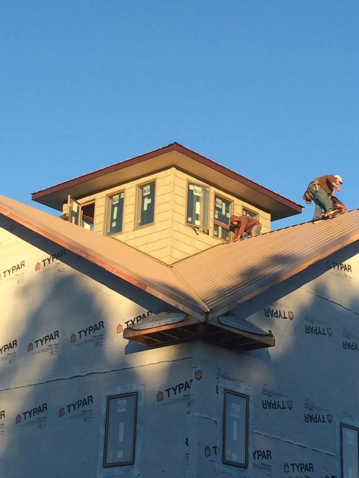 Roofers working around a rooftop cupola on a new metal roof at sunset — Roof Waterproofing in Yazoo City by Roofing Brothers